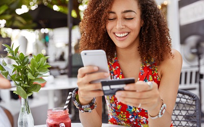 Girl looking at her phone and credit card